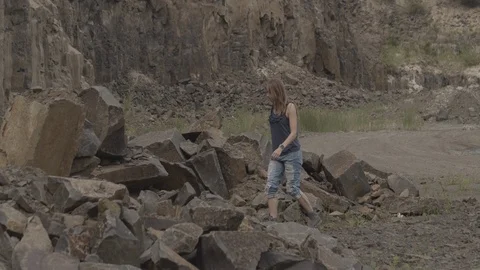 ProRes 4:2:2 log, slow motion footage. Young woman walking in basalt career. Stock Footage 109349264