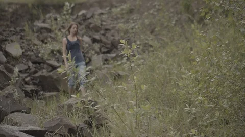 ProRes 4:2:2 log, slow motion footage. Young woman walking in basalt career. Stock Footage 109488219