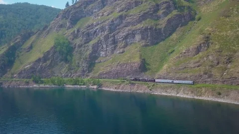 ProRes. Steam train passes through the mountains along the shore. Stock Footage 84165316