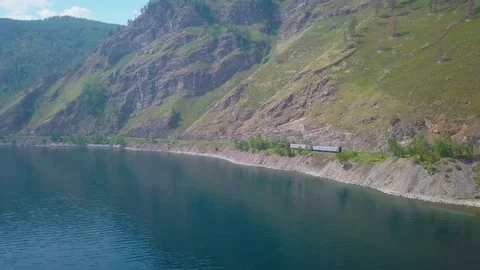 ProRes. Steam train passes through the mountains along the shore. Stock Footage 84364364