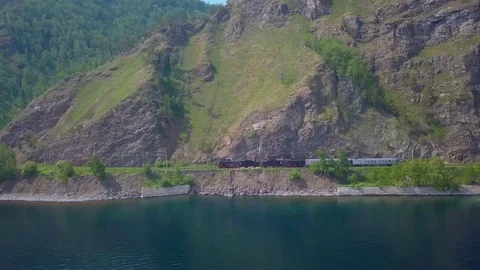 ProRes. Steam train passes through the mountains along the shore. Stock Footage 84364703