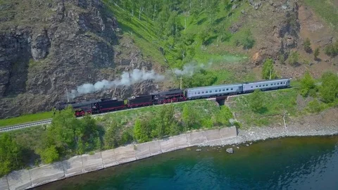 ProRes. Steam train passes through the mountains along the shore. Stock Footage 84365100