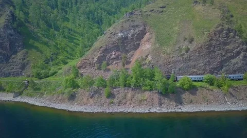 ProRes. Steam train passes through the mountains along the shore. Stock Footage 84365130