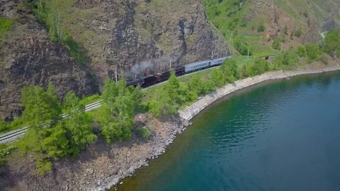 ProRes. Steam train passes through the mountains along the shore. Stock Footage 84366010