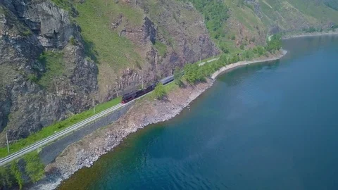 ProRes. Steam train passes through the mountains along the shore. Stock Footage 84366034
