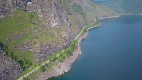 ProRes. Steam train passes through the mountains along the shore. Stock Footage 84367059