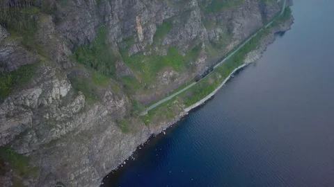 ProRes. Steam train passes through the mountains along the shore. Stock Footage 84368436