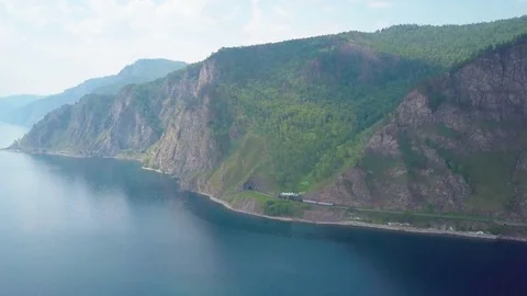 ProRes. Steam train passes through the mountains along the shore. Stock Footage 84369791