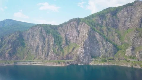 ProRes. Steam train passes through the mountains along the shore. Stock Footage 84369998