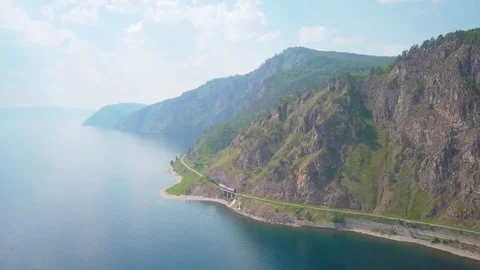 ProRes. Steam train passes through the mountains along the shore. Stock Footage 84370546
