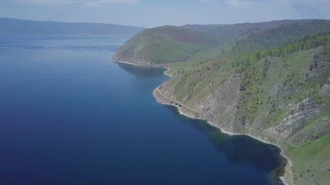 ProRes. Steam train passes through the mountains along the shore. Stock Footage 91201267