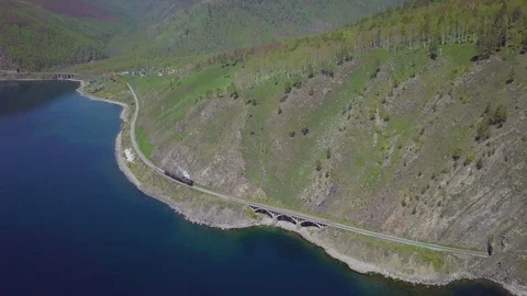 ProRes. Steam train passes through the mountains along the shore. Stock Footage 91201417
