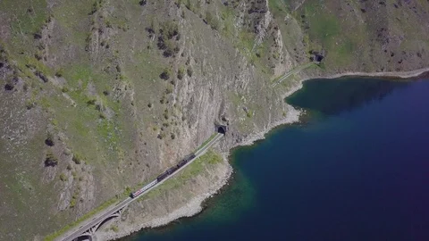 ProRes. Steam train passes through the mountains along the shore. Stock Footage 91201429