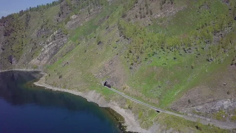 ProRes. Steam train passes through the mountains along the shore. Stock Footage 91201603