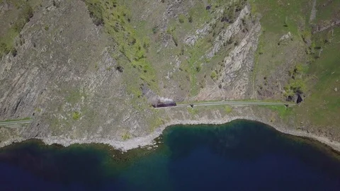 ProRes. Steam train passes through the mountains along the shore. Stock Footage 91201672