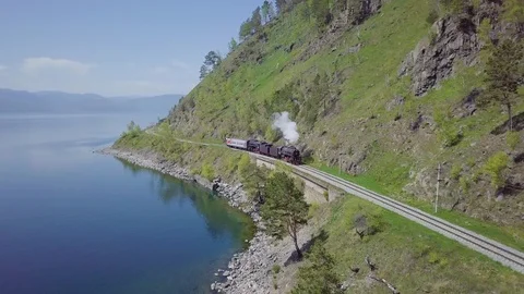 ProRes. Steam train passes through the mountains along the shore. Stock Footage 91201905