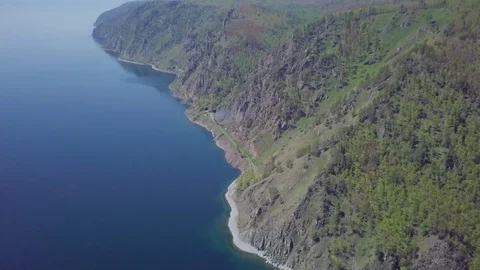 ProRes. Steam train passes through the mountains along the shore. Stock Footage 91201996