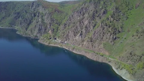 ProRes. Steam train passes through the mountains along the shore. Stock Footage 91202217