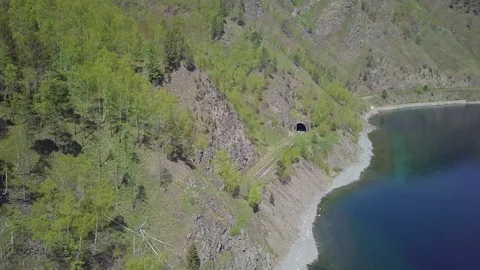ProRes. Steam train passes through the mountains along the shore. Stock Footage 91210790