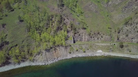 ProRes. Steam train passes through the mountains along the shore. Stock Footage 91211062