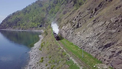 ProRes. Steam train passes through the mountains along the shore. Stock Footage 91211155