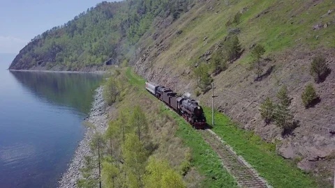 ProRes. Steam train passes through the mountains along the shore. Stock Footage 91211252