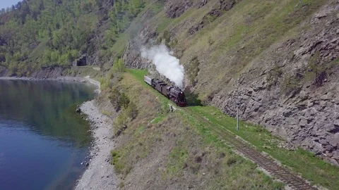 ProRes. Steam train passes through the mountains along the shore. Stock Footage 91211321