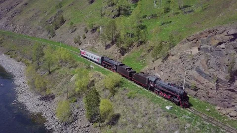 ProRes. Steam train passes through the mountains along the shore. Stock Footage 91211421