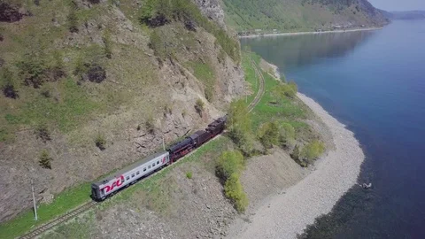 ProRes. Steam train passes through the mountains along the shore. Stock Footage 91211463