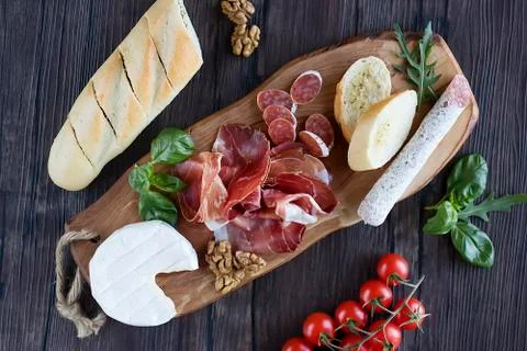 Prosciutto, bread, olives, walnut, mozzarella, salami, basil and cherry tomat Stock Photos