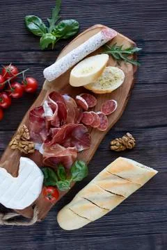Prosciutto, bread, olives, walnut, mozzarella, salami, basil and cherry tomat Stock Photos