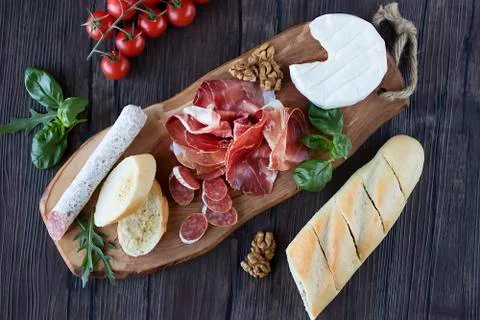 Prosciutto, bread, olives, walnut, mozzarella, salami, basil and cherry tomat Stock Photos