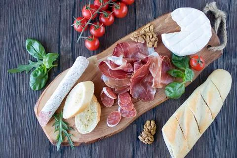 Prosciutto, bread, olives, walnut, mozzarella, salami, basil and cherry tomat Stock Photos
