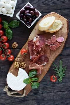 Prosciutto, bread, olives, walnut, mozzarella, salami, basil and cherry tomat Stock Photos