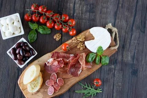 Prosciutto, bread, olives, walnut, mozzarella, salami, basil and cherry tomat Foto stock