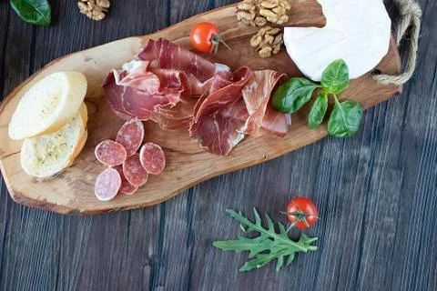 Prosciutto, bread, olives, walnut, mozzarella, salami, basil and cherry tomat Stock Photos