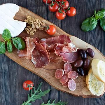 Prosciutto, bread, olives, walnut, mozzarella, salami, basil and cherry tomat Stock Photos