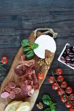 Prosciutto, bread, olives, walnut, mozzarella, salami, basil and cherry tomat Stockfoto's