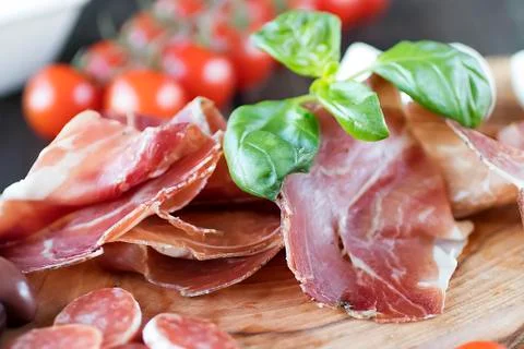 Prosciutto, bread, olives, walnut, mozzarella, salami, basil and cherry tomat Stock Photos