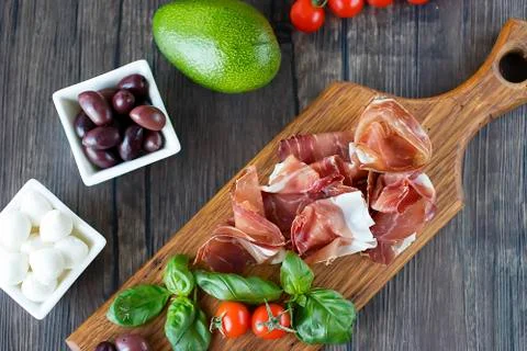 Prosciutto, bread, olives, walnut, mozzarella, salami, basil and cherry tomat Stock Photos