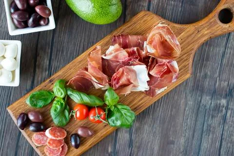 Prosciutto, bread, olives, walnut, mozzarella, salami, basil and cherry tomat Foto stock