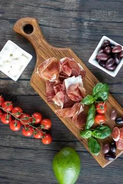 Prosciutto, bread, olives, walnut, mozzarella, salami, basil and cherry tomat Stock Photos