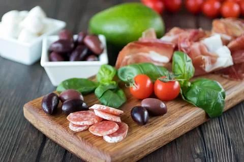 Prosciutto, bread, olives, walnut, mozzarella, salami, basil and cherry tomat Stock Photos