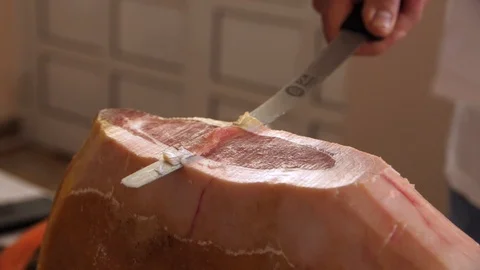 Prosciutto dry-cured ham being sliced with long knife Stock Footage 119392687
