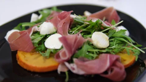Prosciutto mozzarella arugula, Persimmon salad Traditional Italian antipasti in Stock Footage 302672800