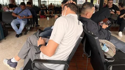 Prospective passengers wait for the plane by playing with gadgets. Stock Photos