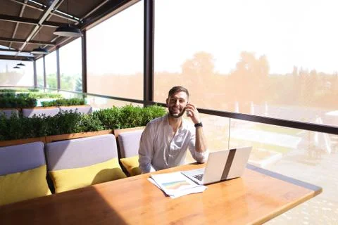 Prosperous sales manager reading documents, using laptop at tabl 写真素材