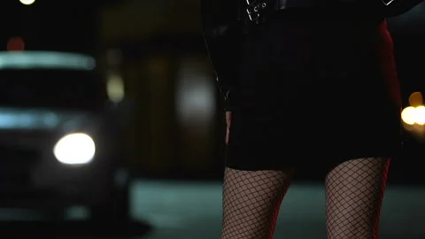 Prostitute in checkered tights waiting clients on road, upset about passing car Stock Footage 114693834