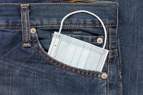 Protective face mask is lying in side pocket of jeans. Concept new lifestyle. Stock Photos