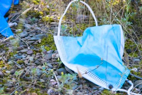 Protective face mask thrown to the floor after use on to the nature. Contamin Stock Photos